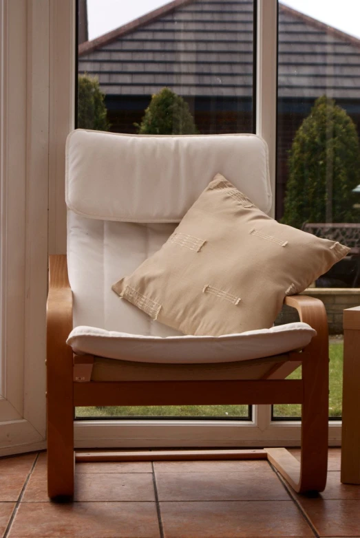 white and tan chair sitting in front of a window