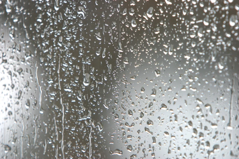 rain drops falling off of a window in the daytime