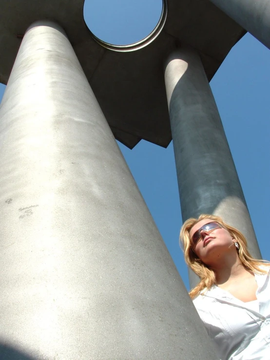 a woman that is posing for a picture next to two tall metal structures