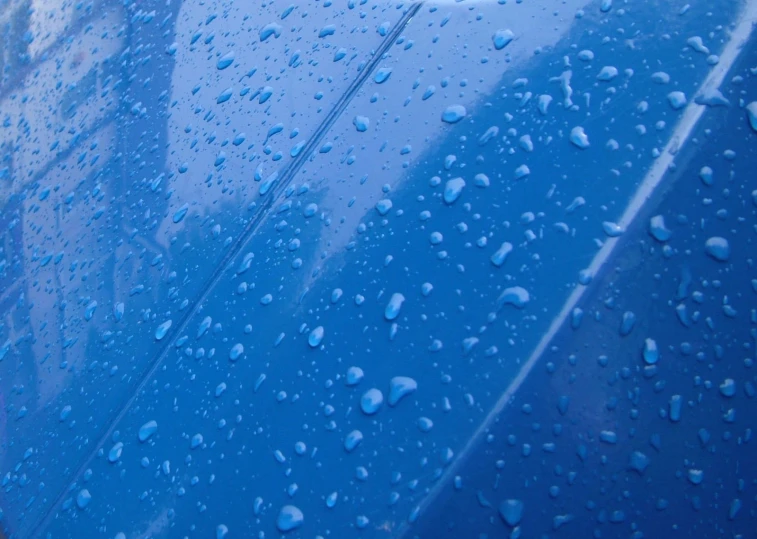 a large blue car covered in water and drops