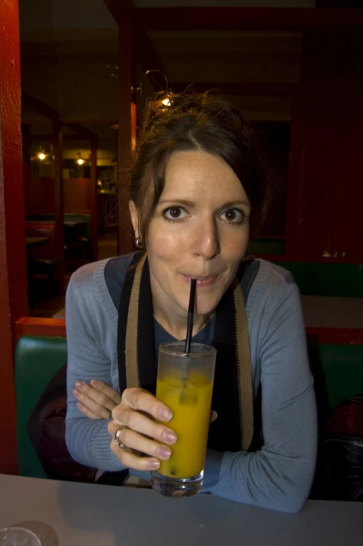 a woman drinking juice with a straw in her mouth