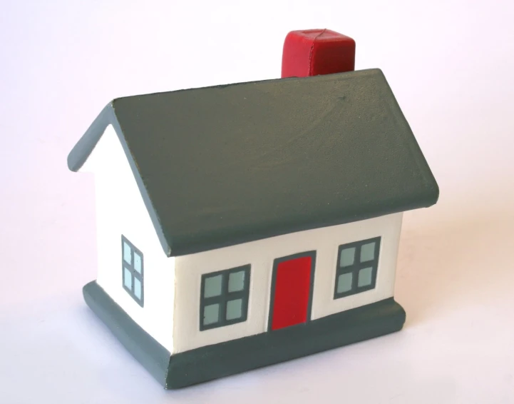 a small toy house with red doors on white surface