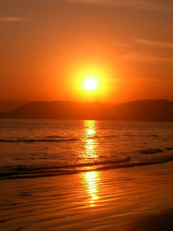 a bright orange sunset and a surfer in silhouette on the water