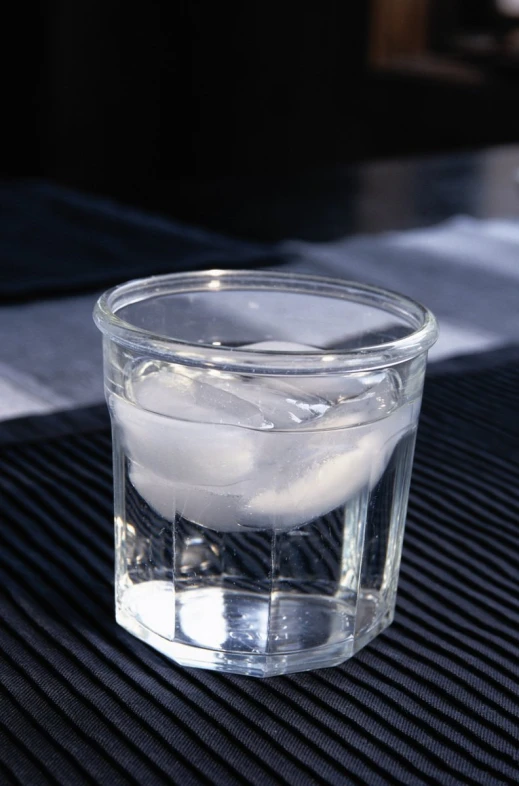 a glass with some water sitting on a surface