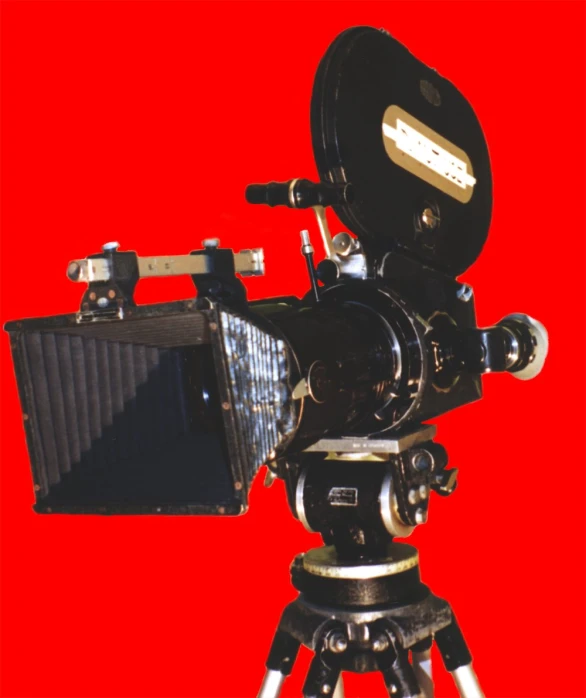 the back end of an old style video camera with a tripod and lens