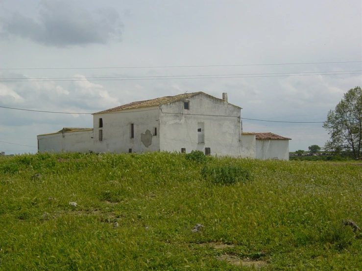 the abandoned house is in a field of green grass