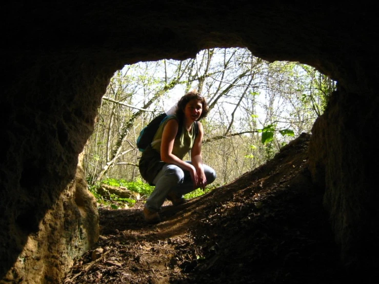 a young woman squatting down in a cave