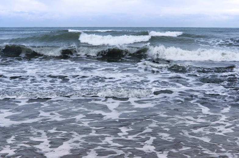 waves crashing on a beach area in the middle of the ocean