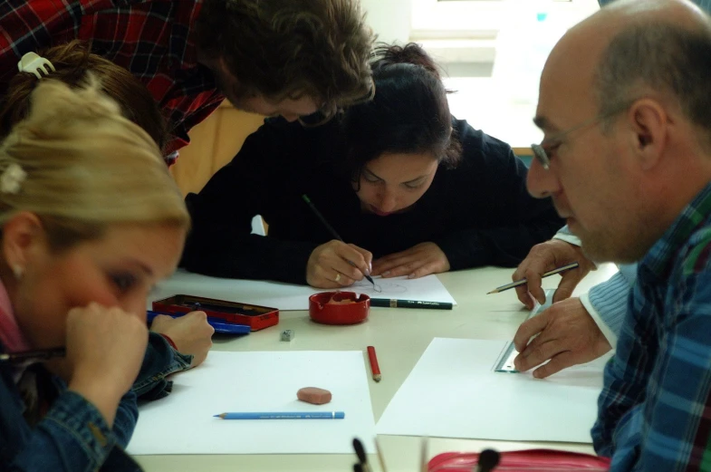 a group of people with pencils are looking at papers