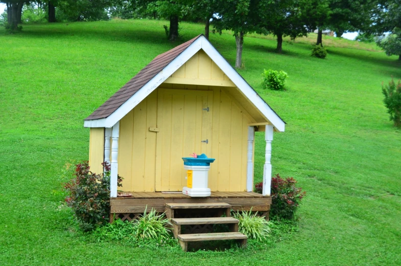 a small yellow house sits in a grass field