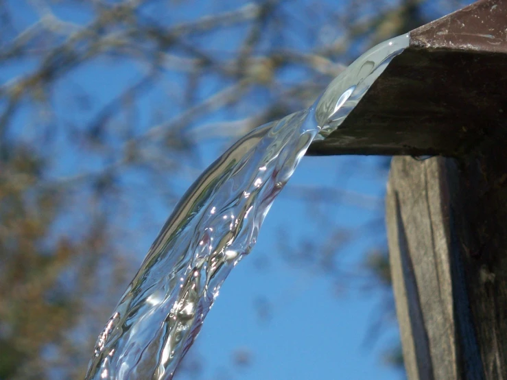 the water is running down the side of the wooden spout