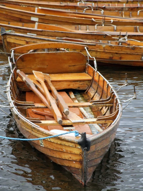 a wooden canoe tied up to another boat