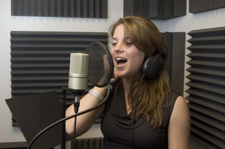 woman singing into a microphone with headphones on