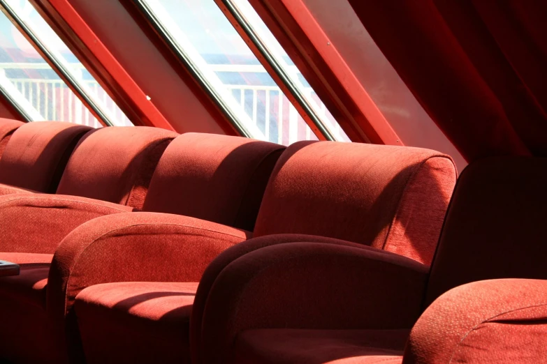 several red seats sitting side by side in front of a window