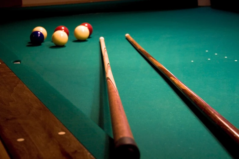 a pool table has bill balls and cues sitting on it