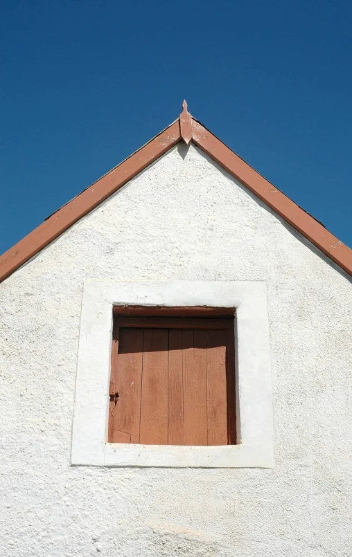 a small white structure with a red door and window