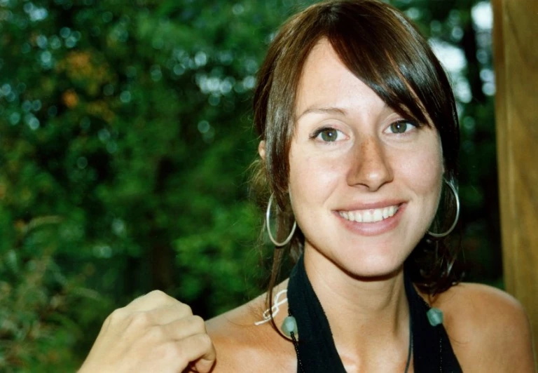 a woman in a black shirt standing in a wooded area