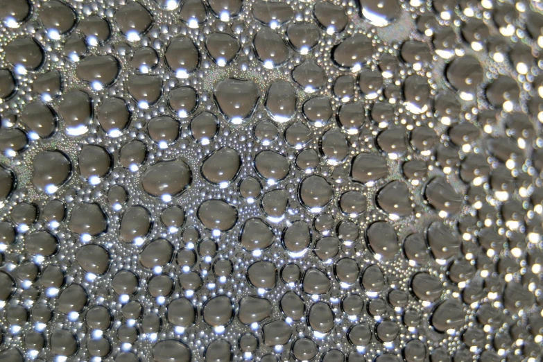 rain drops are reflecting light on the surface of a reflective glass
