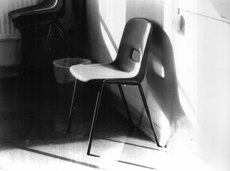 a black and white po of a chair in a corner next to a wall