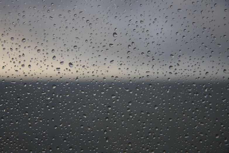 a window with water on the glass with sky and clouds in the background