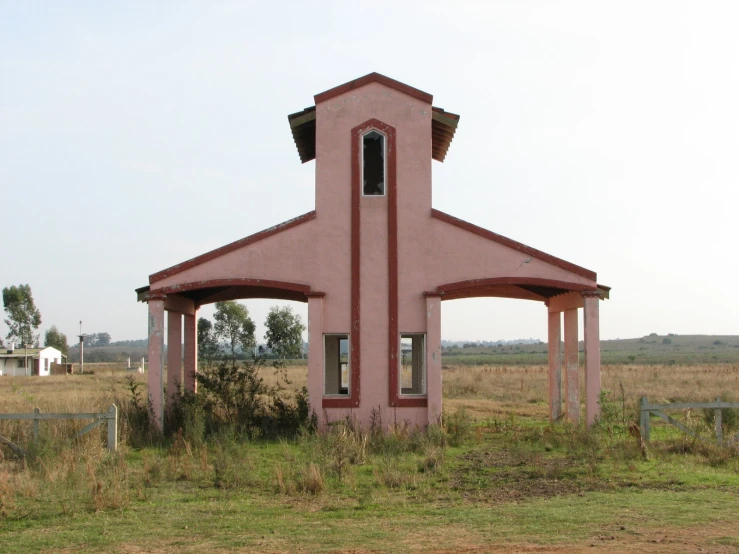 a small red structure sits in the middle of a field