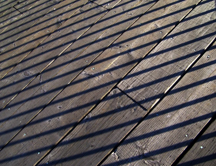 a wood deck that has only lines of wood and some leaves