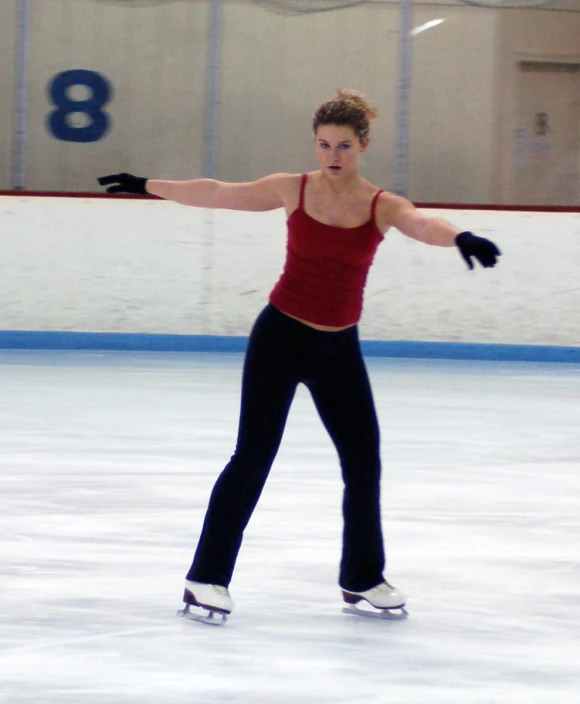 a woman standing on a ice rink holding onto one hand