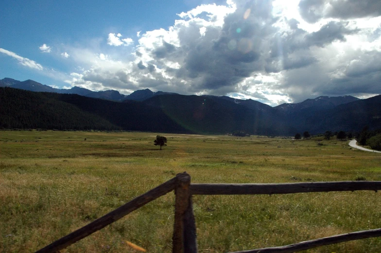 a field with a fence and dirt road