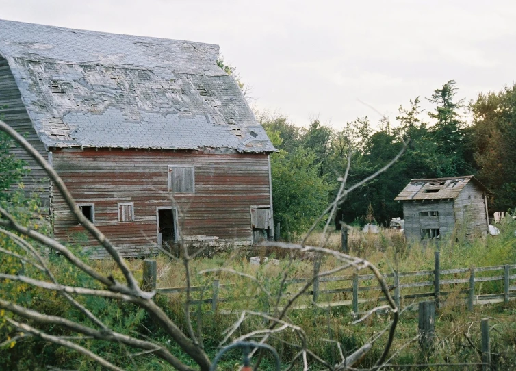 an old wooden barn stands in a field