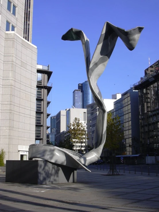 a tall modern sculpture sitting in a large plaza