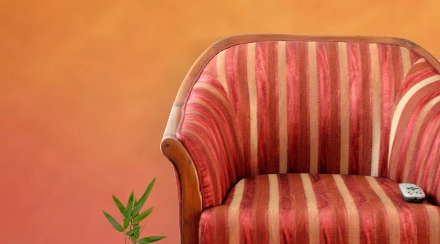 a striped armchair sits next to a potted plant