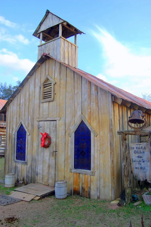 a small wooden church with blue windows and a clock tower