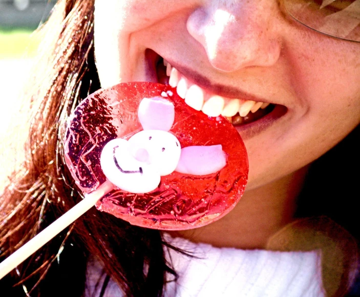 a girl holding a lollipop with red and white designs