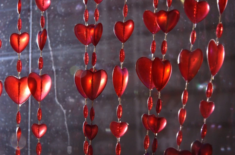 several red hearts hanging from a string on a window