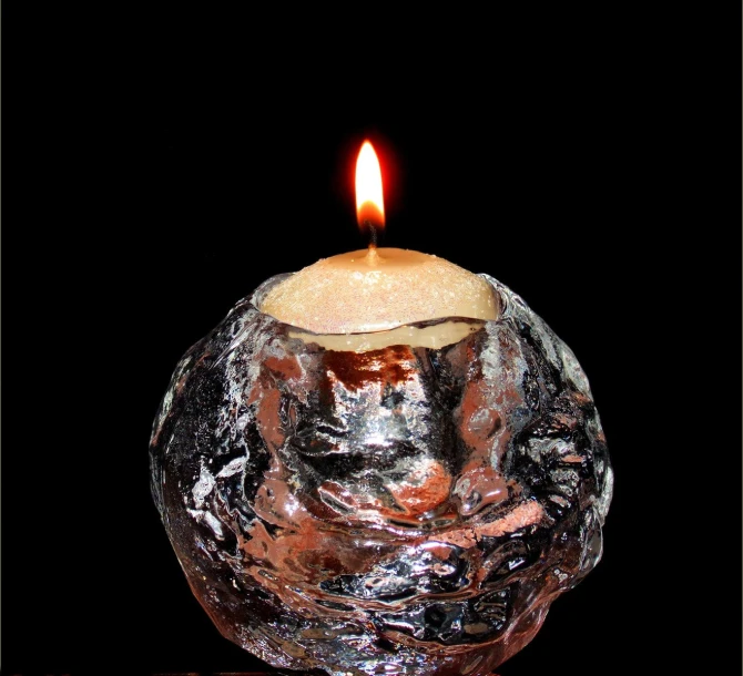 a glass candle sits on top of a black surface