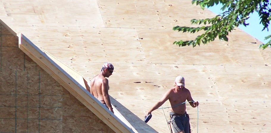 two guys working on a roof top next to a building