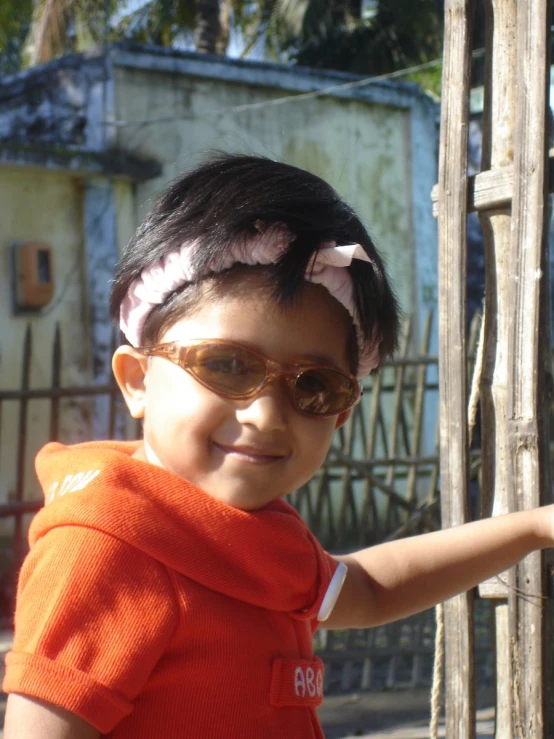 a  wearing sunglasses leaning against a fence