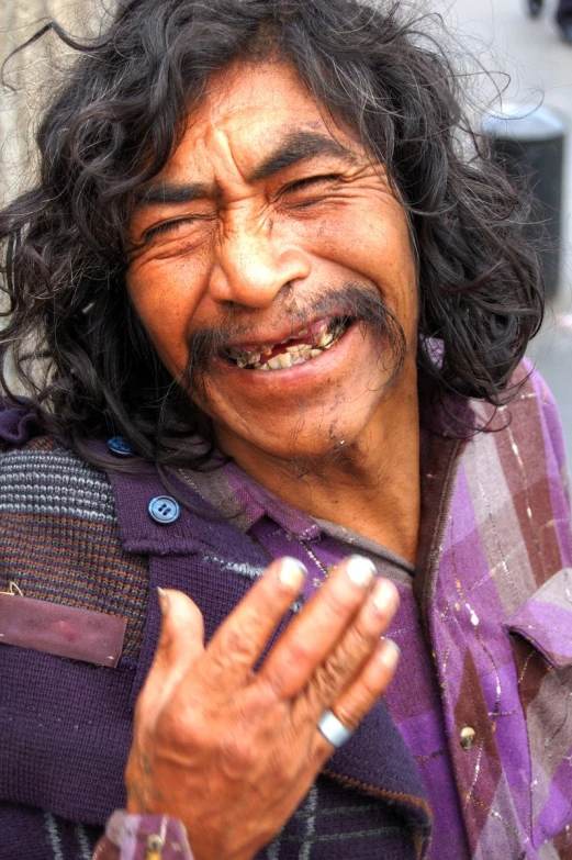 a man in purple shirt laughing with his hand folded