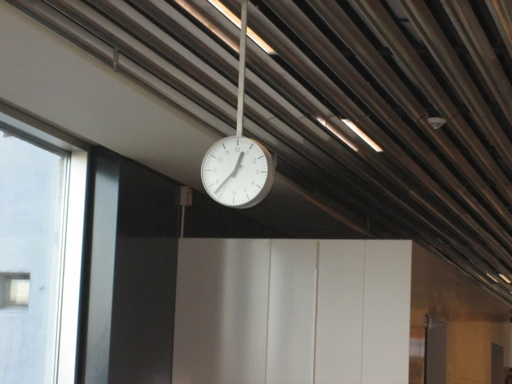 a clock hanging from the ceiling above a kitchen