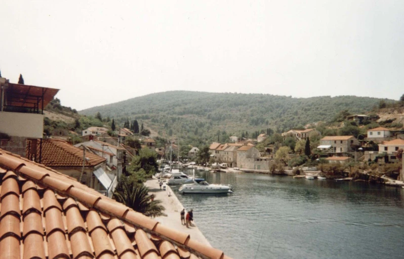 a small boat is on the water with homes and hills