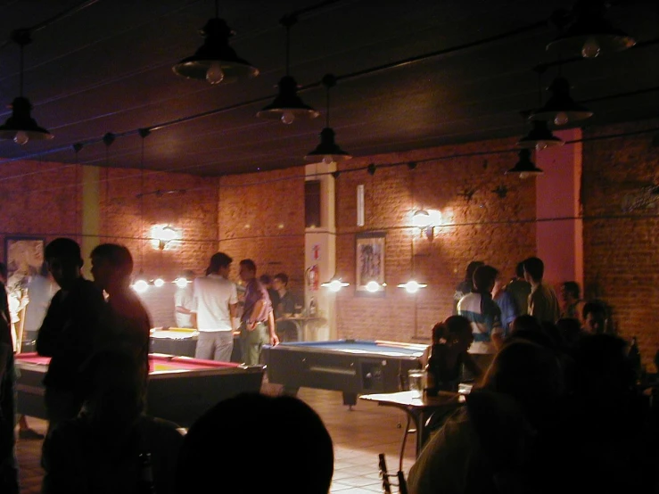 people gather inside of a dark brick building to watch an indoor pool