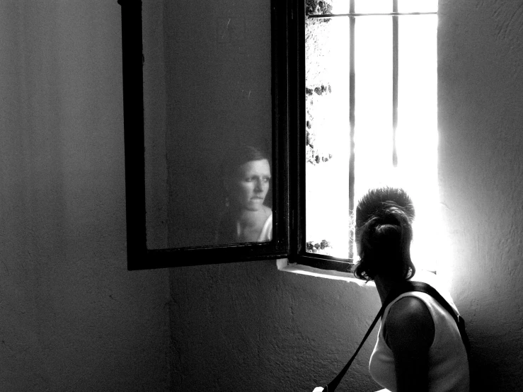 black and white pograph of woman looking at herself in the mirror