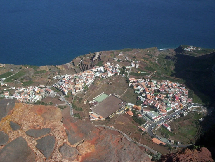 an aerial view shows a town built at the base of a cliff