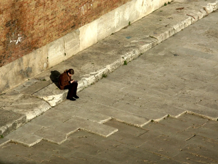 a woman sitting on steps beside a brick building