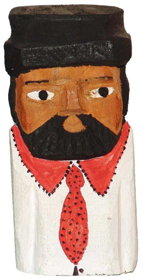 a carved wooden figure wearing a hat, scarf, and necktie