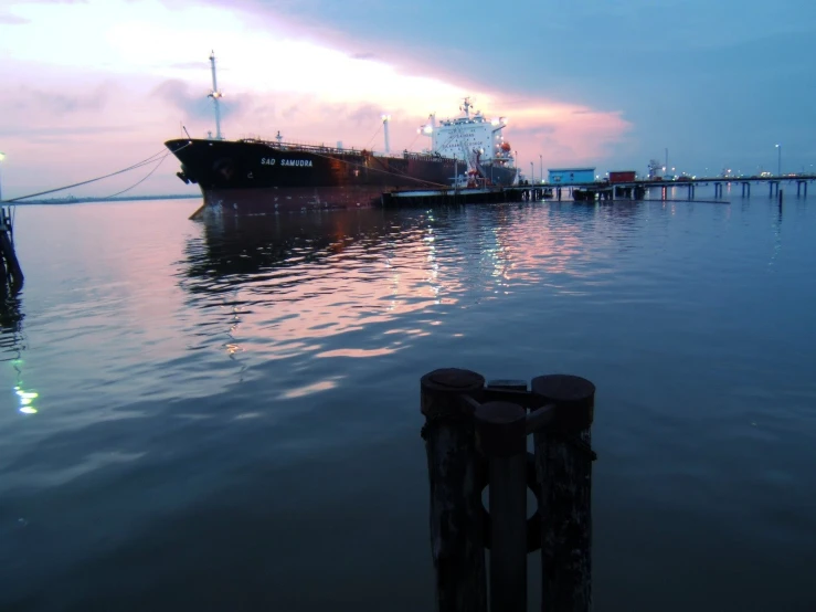 a large ship docked next to a pier at sunset