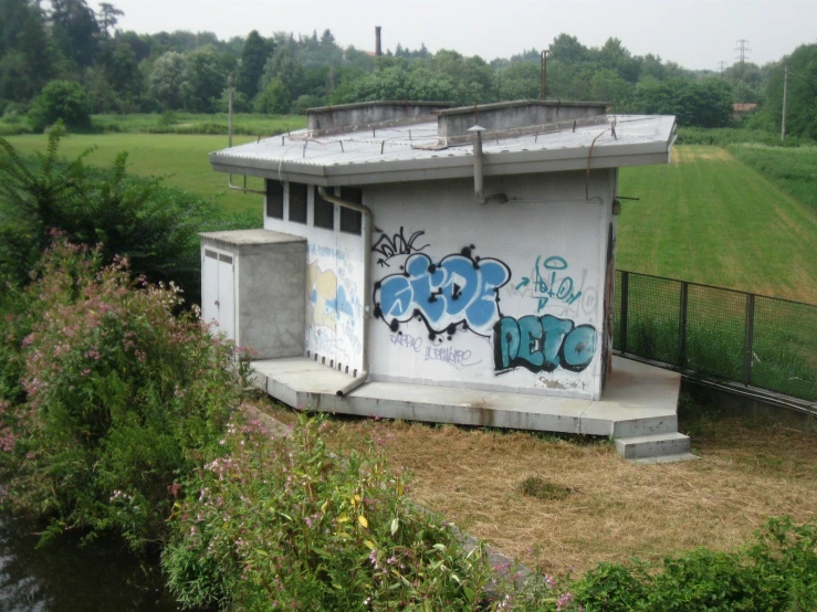 a small building with graffiti on it sitting on the grass
