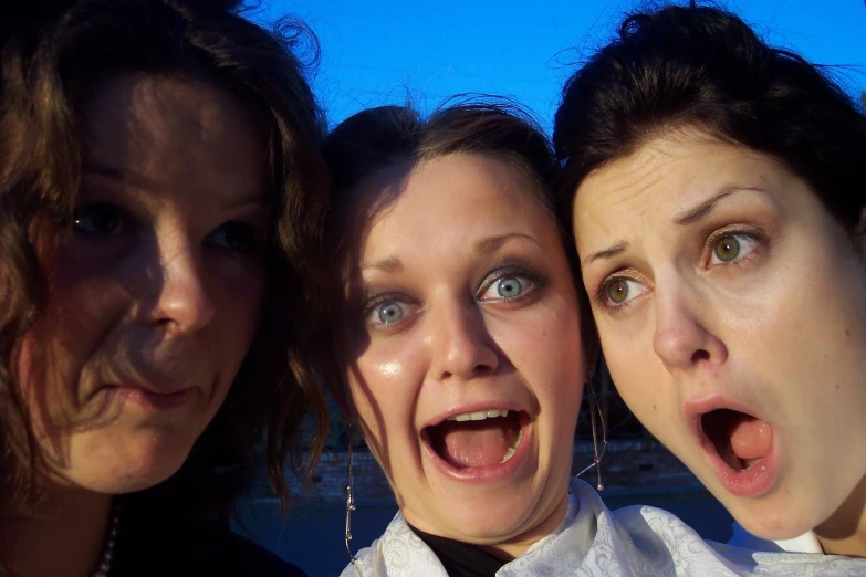 three women take a picture together outside on the beach