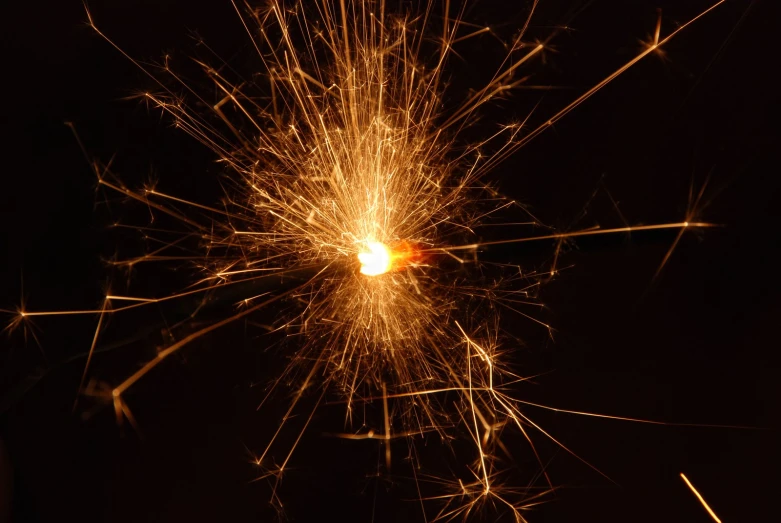 a yellow sparkler is lit in the dark