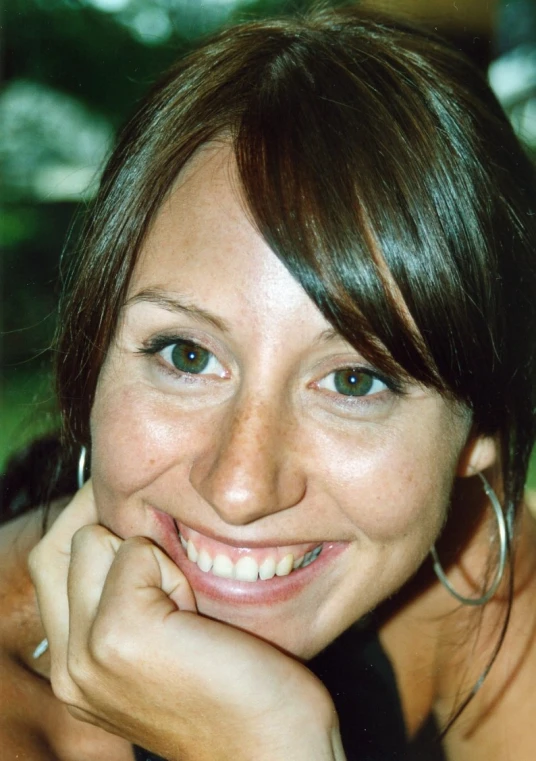 a woman with a hoop earrings smiling for the camera